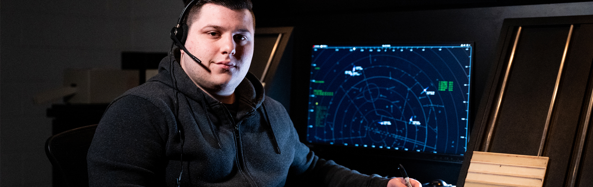 Person wearing a headset sitting in front of a computer screen displaying radar data.