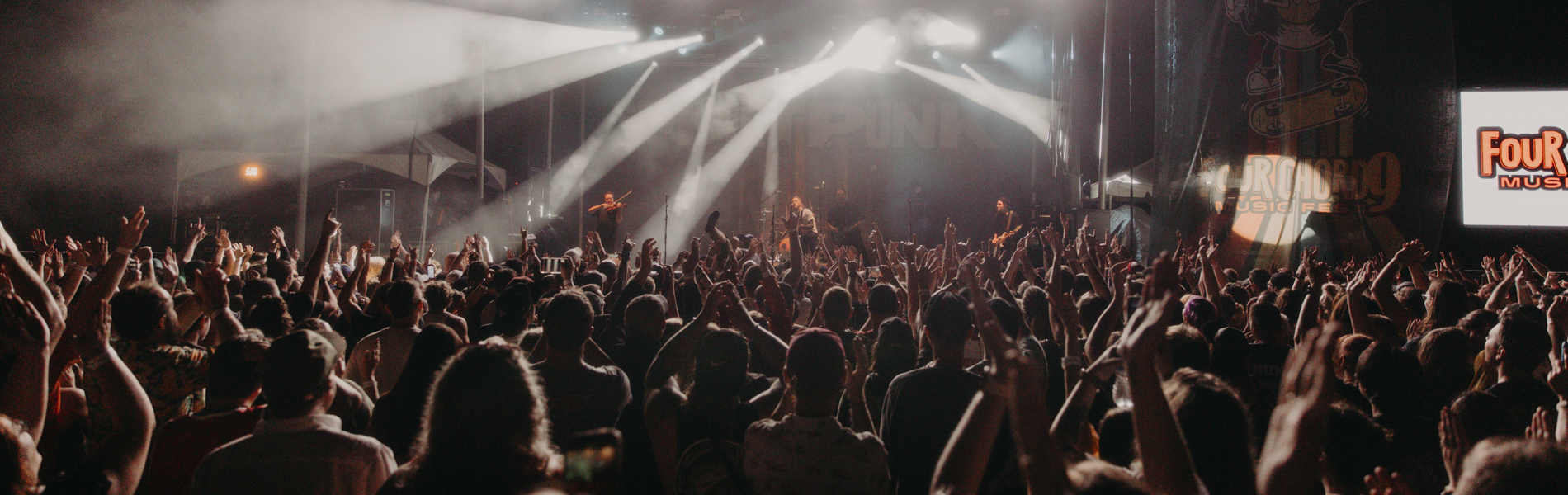 Crowd of people enjoying a live concert at night, with visible stage lights.
