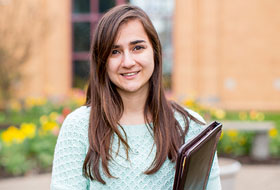 A student carries a book outside at La Roche University.