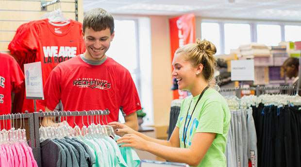 Two students browse apparel in the La Roche University campus bookstore.