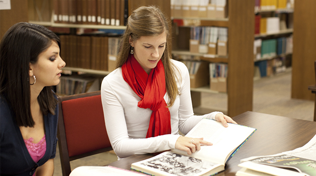 Two students look at a book together in the library at La Roche University.
