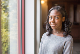 Female student standing near window outside Magdalen Chapel at La Roche University