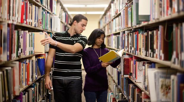 2 students looking for books in library