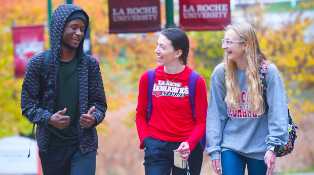 Three La Roche University students walking on campus on a fall day. 
