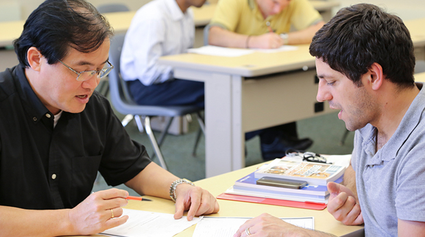 Two male participants of La Roche's Clergy and Religious Summer English Institute practice English language skills in the classroom.