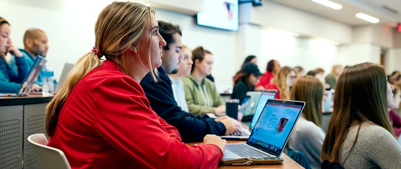 La Roche University students attending a lecture in a classroom, with laptops open for note-taking.